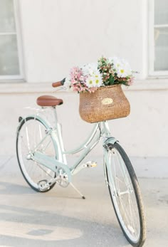 a bicycle with a basket full of flowers on the handlebars is parked in front of a building