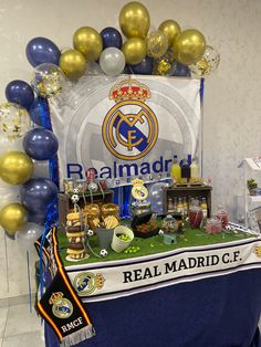 a table topped with balloons and confetti next to a sign that reads real madrid