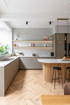 a modern kitchen with wooden floors and white counter tops, along with an island in the middle