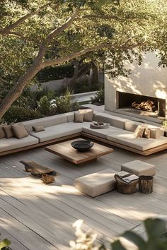 an outdoor living area with couches, tables and a fire place in the background