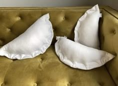 two white pillows sitting on top of a green couch