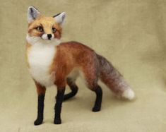 a needle - felt fox is standing on a beige background