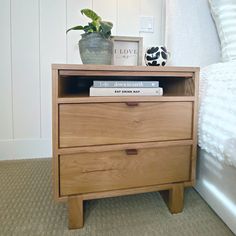 a nightstand with two books and a plant on top