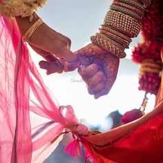 two people holding hands with bracelets and jewelry on their wrists, while one holds the other's hand