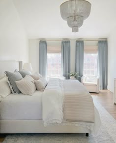 a large white bed sitting in a bedroom next to two windows