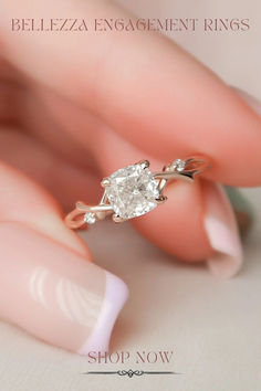 a woman's hand holding a ring with a white diamond on the middle of it