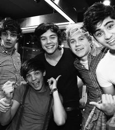 four young men posing for the camera in a black and white photo with one pointing at the camera