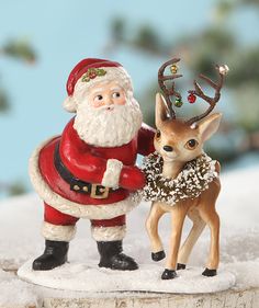 a santa clause and reindeer figurine on top of snow