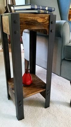 a small wooden table with a red vase on it's shelf next to a couch