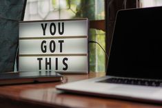 a laptop computer sitting on top of a desk next to a sign that says you got this