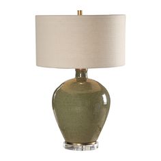 a green glass table lamp with a white shade on the base and a beige linen lampshade