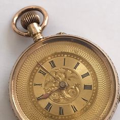 ANTIQUE Ladies 14k Gold Fob/Pocket Watch. c.1900. Beautifully floral engraved 14k gold case having  vacant cartouche to rear of case. Guilded inner back. Unusual guilded dial having decorative engine turning to outside of dial and engraved scroll work to centre of dial with black roman numerals. Guilded hands.  Swiss movement. Bow wound and pin hand set. Watch dimensions - 33mm diameter. Height inc bow 48mm. This watch is sold with a 12 month guarantee from MBHI certificated watchmakers, established 1947. All watches will be serviced before shipping hence the 2-3 week dispatch. Please note - Watches are not waterproof unless otherwise stated and it is recommended not to wear them near water (i.e. washing hands, washing up, shower, swimming etc). Victorian Yellow Gold Pocket Watch With Chronometer, Victorian Gold Watch With Chronometer, Victorian Style Gold Watch With Chronometer, Victorian Yellow Gold Pocket Watch Collectible, Victorian Yellow Gold Pocket Watch For Collectors, Victorian Engraved Gold Watches, Engraved Yellow Gold Pocket Watch With Round Dial, Antique Yellow Gold Pocket Watch Collectible, Victorian Yellow Gold Pocket Watch For Formal Occasions