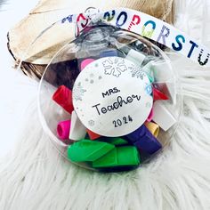 a glass container filled with lots of colorful hair clips and a name tag that says mrs teddyboy 2011