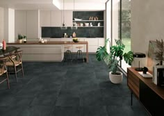 a kitchen with black tile flooring and white cabinetry next to a dining room table