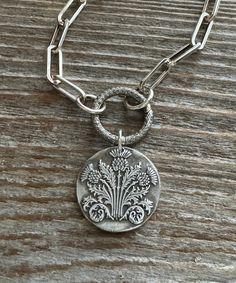 "This silver Scottish Thistle pendant is made from .999 fine silver. Fine silver has a higher silver content than sterling silver. The impression is from a wax seal stamp. It is 1\" diameter. The pendant is made from a wax seal stamp impression. Each pendant is made to order and each unique. This listing is for the pendant only." Silver Etched Necklace With Flower Pendant, Silver Medallion Necklace With Etched Details, Silver Etched Medallion Necklace, Artisan Silver Necklace With Coin Pendant, Silver Stamped Round Disc Jewelry, Stamped Silver Round Disc Jewelry, Nature-inspired Silver Etched Necklaces, Silver Etched Nature-inspired Necklaces, Silver Round Stamped Necklaces