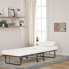 a white bed sitting on top of a wooden floor next to a book shelf filled with books