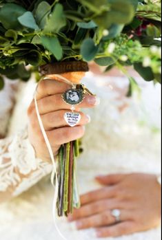 a bride holding a bouquet of greenery with her wedding ring on it's finger