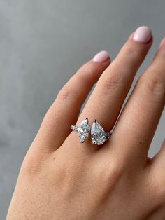 a woman's hand with a diamond ring on top of her finger and the other hand holding an engagement ring