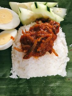 rice, boiled egg and meat on a leafy green plate with sliced cucumbers