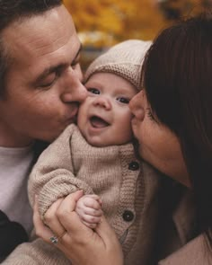 a man and woman kissing their baby while he is holding it up to his face