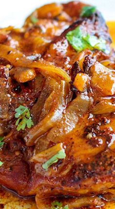 a close up of food on a plate with meat and onions in sauce, garnished with parsley