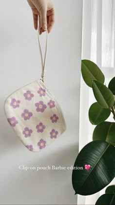 a hand is holding a small pouch with flowers on it and hanging from the side