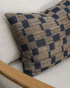 a blue and brown pillow sitting on top of a white couch next to a wooden headboard