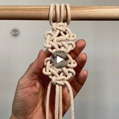 a person holding up a piece of rope with an object in the middle of it