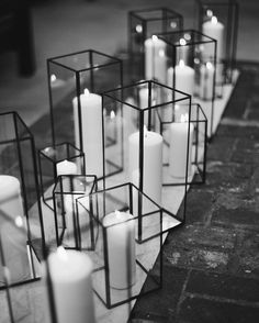 many white candles are placed in glass containers on the brick floor, along with one another