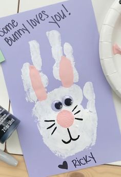 a paper plate with a bunny handprint on it next to some crafting supplies