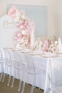 a table set up for a baby's first birthday party with pink and white balloons