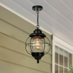 a light hanging from the side of a house with a potted plant next to it