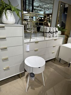 an assortment of white furniture and accessories on display at a showroom or home decor store