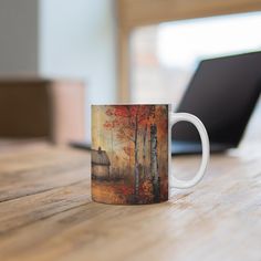 a coffee mug sitting on top of a wooden table next to a laptop computer,