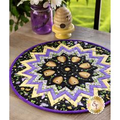 a purple and black table mat on a wooden table with flowers in vases next to it