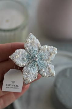 a close up of a person holding a small brooch with pearls and beads on it