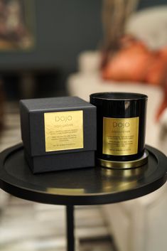 two candles sitting on top of a table next to a black box with gold foil