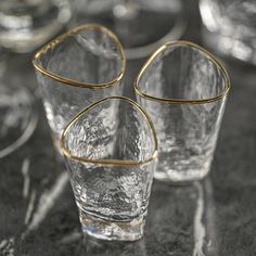 several clear glass cups with gold rims on a black tablecloth covered table top