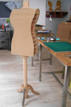 a mannequin made out of cardboard sitting on top of a wooden table