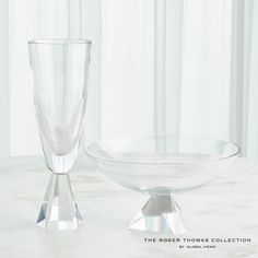 two clear glass vases sitting on top of a white table next to each other