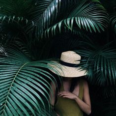 a woman wearing a straw hat standing in front of palm trees with the caption's name on it