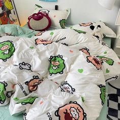 an unmade bed in a child's bedroom with cartoon characters on the comforter