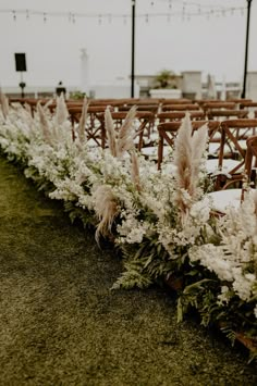 rows of chairs with flowers and greenery on them