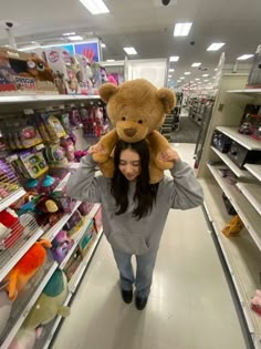 a woman is walking down the aisle with a teddy bear on her shoulders in a store