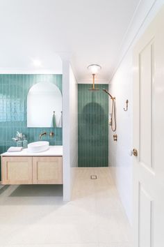 a bathroom with two sinks and a shower in the corner, along with green tiles on the walls