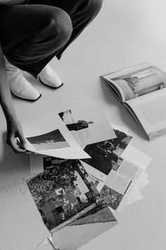 a person sitting on the floor next to some books and papers that have been torn off