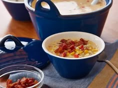 two bowls filled with soup on top of a wooden table next to a blue pot