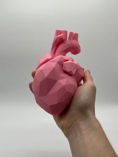 a hand holding a pink origami heart