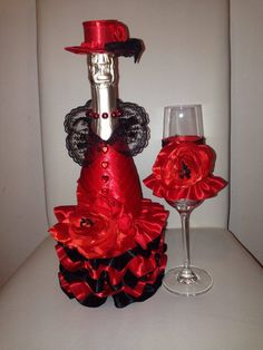 a red dress and wine glass sitting on top of a white table next to each other