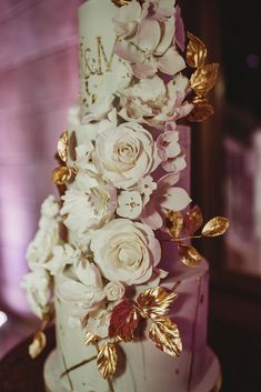 a wedding cake with white flowers and gold leaves